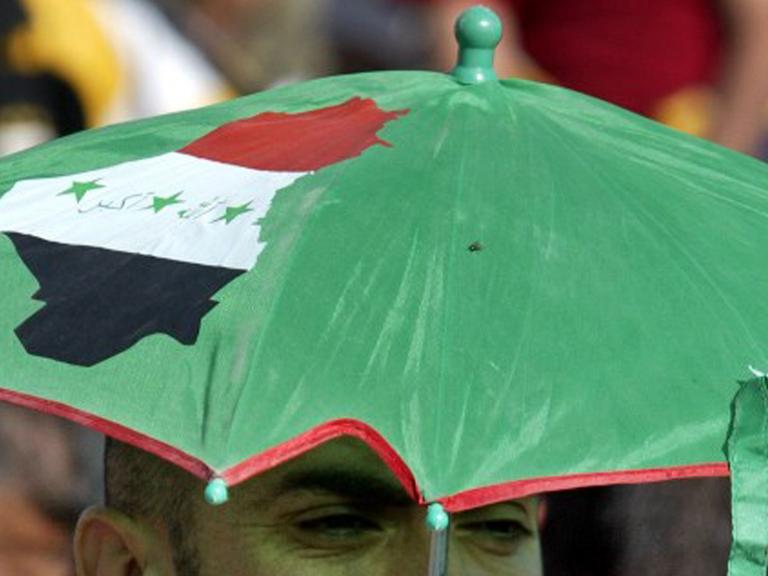 Ein irakischer Shiit trägt einen Schirm mit dem Umirssen des Iraks.