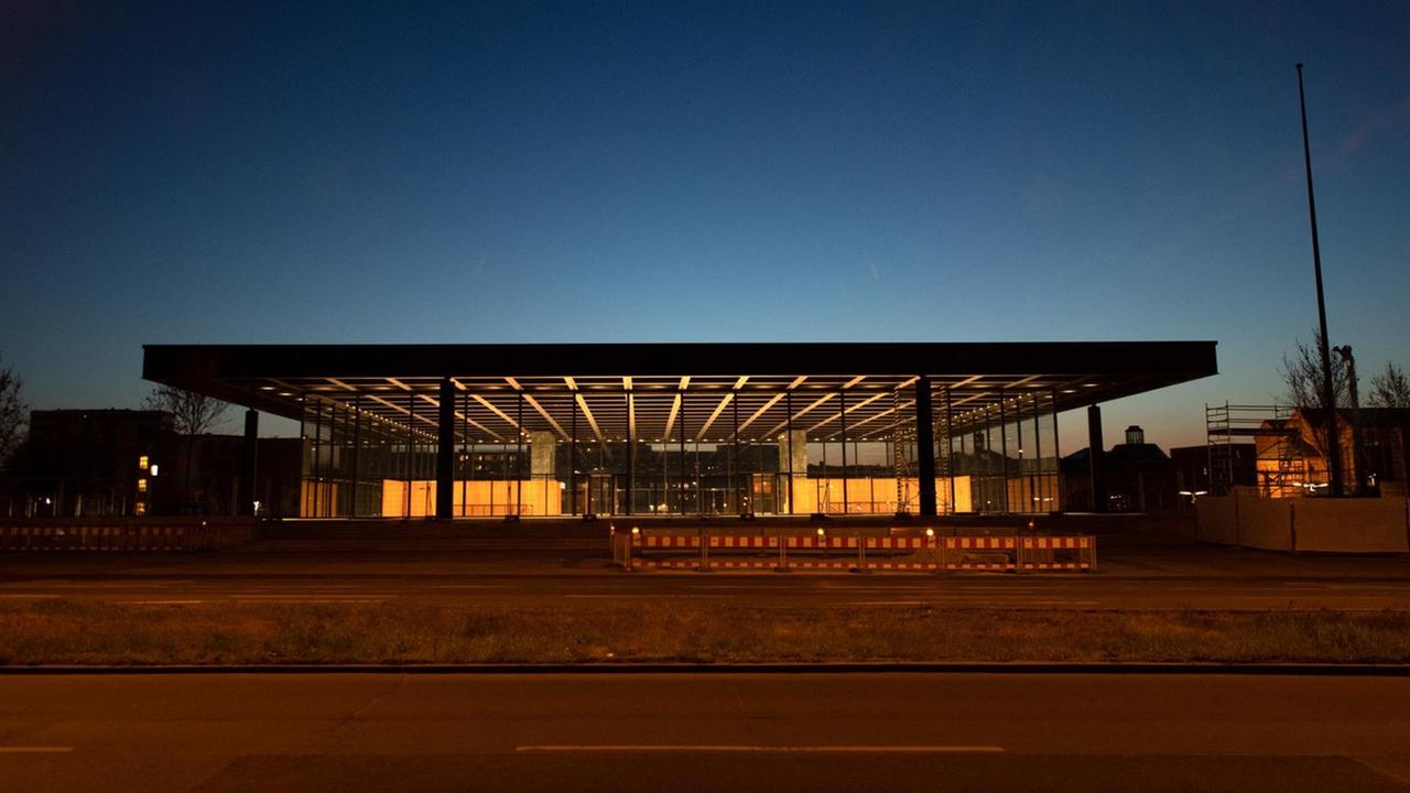 Das flache Gebäude mit einem großen Stahl-Dach und Glas-Wänden ist am Abend hell beleuchtet