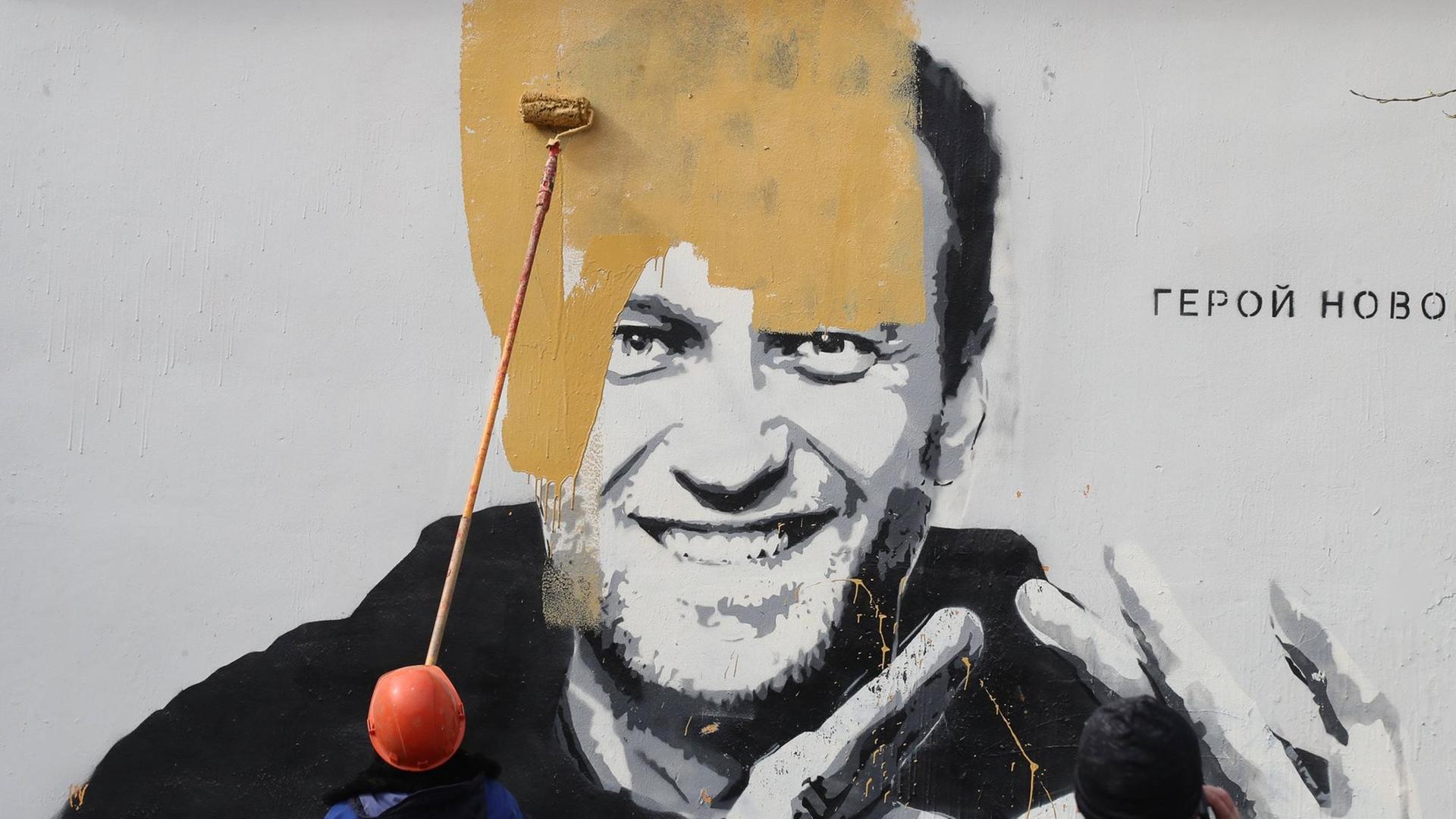 Ein Wandbild auf einem Gebäude in St. Petersburg, das den russischen Oppositionellen Alexej Nawalny zeigt mit dem Schriftzug "Der Held einer neuen Zeit", wird kurz nach seiner Entdeckung übermalt.