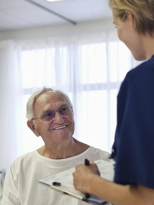 Eine Krankenpflegerin im Gespräch mit einem älteren Patienten