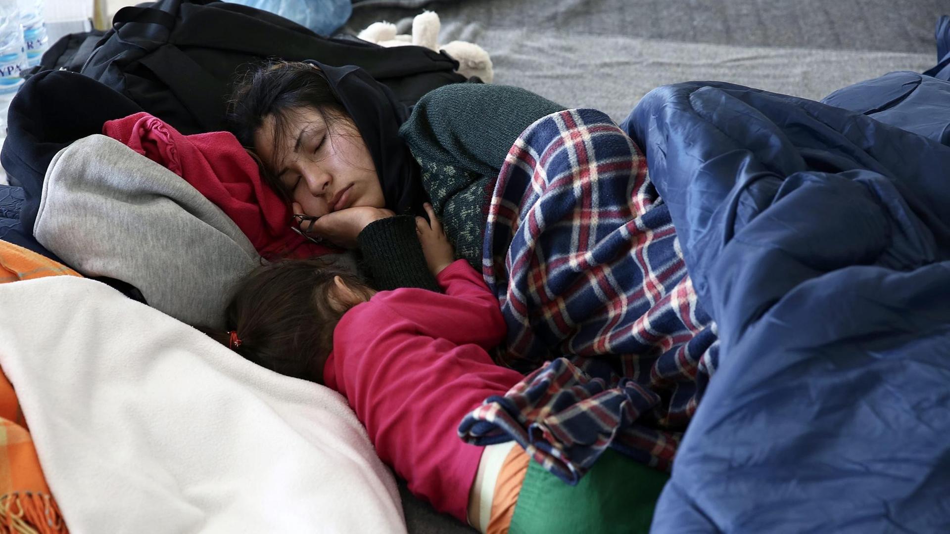 Eine junge Frau und ihr Kind schlafen in einem provisorischen Flüchtlingslager im alten Flughafen von Athen.
