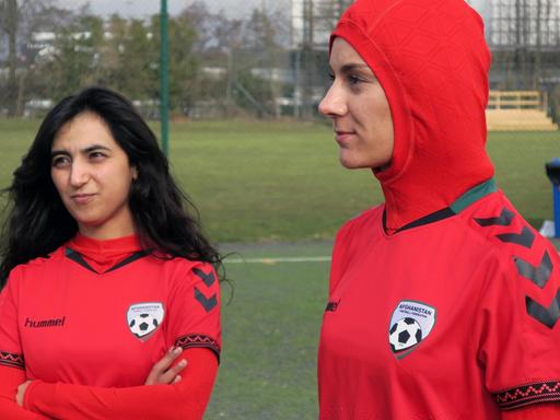 Shabnam Mabarz und Khalida Popal (l.), stehen im Trikot der afghanischen Frauen-Nationalmannschaft auf einem Fußballfeld.