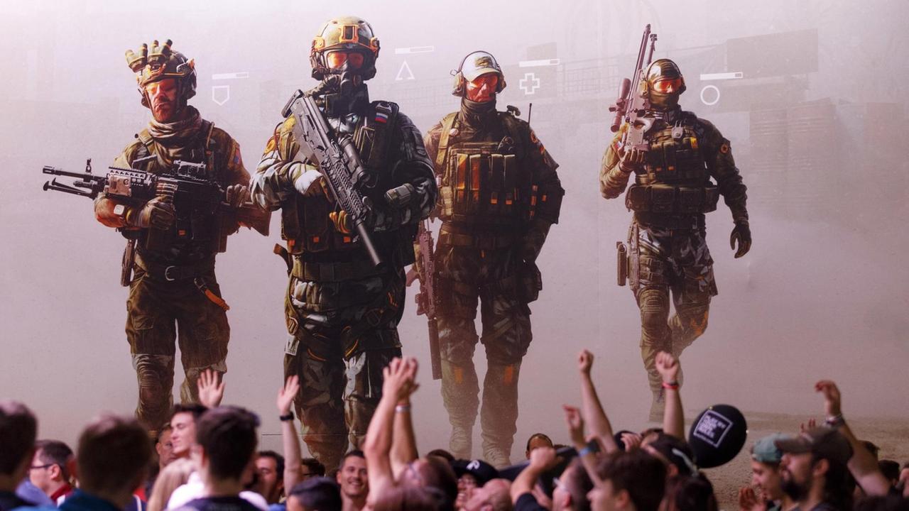 Junge Männer recken die Hände in die Luft vor einem Werbeplakat des Egoshooters Caliber.