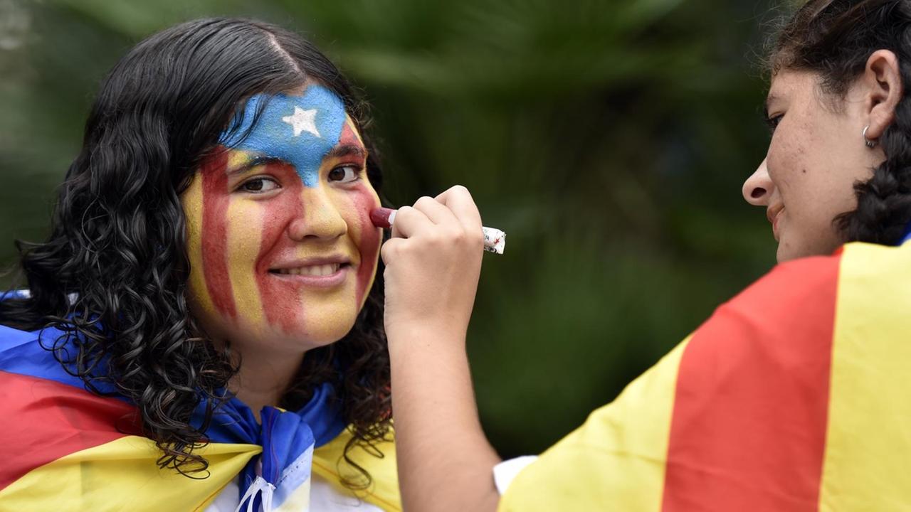 Zwei junge Frauen schminken sich in den katalonischen Nationalfarben.