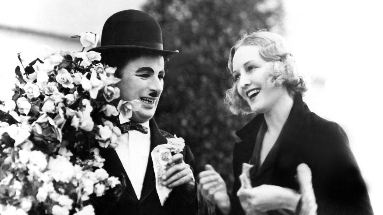 Ein schwarzweißer Filmausschnitt zeigt Charlie Chaplin als Tramp und Virginia Cherrill als blindes Blumenmädchen in "Lichter der Großstadt" von 1931