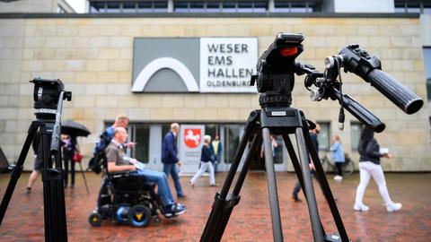 Personen sind während des letzten Prozesstages des Patientenmörders Niels Högel vor der Weser-Ems-Halle (Oldenburg in Niedersachsen) hinter zwei Filmstativen