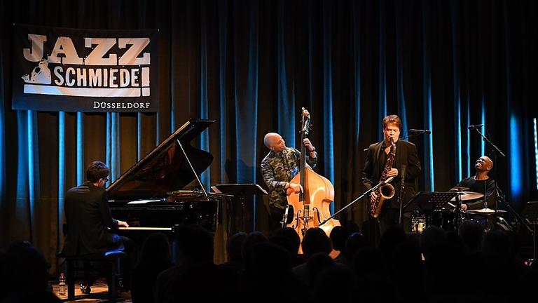 Vier Musiker spielen vor einem dunklen Vorhang auf der Bühne der Jazz-Schmiede Düsseldorf