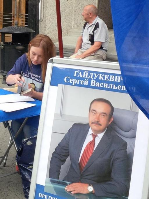 Auf einer Straße in Weißrussland sammeln Kandidaten Unterschriften. Auf einem Wahlplakat ist der Kandidat Sergej Wassilewitsch Gajdukewitsch abgebildet, er ist einer der Bewerber um das Präsidentenamt und Vorsitzender der Liberaldemokratischen Partei.
