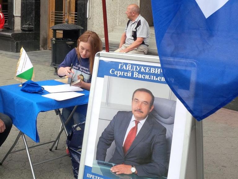 Auf einer Straße in Weißrussland sammeln Kandidaten Unterschriften. Auf einem Wahlplakat ist der Kandidat Sergej Wassilewitsch Gajdukewitsch abgebildet, er ist einer der Bewerber um das Präsidentenamt und Vorsitzender der Liberaldemokratischen Partei.