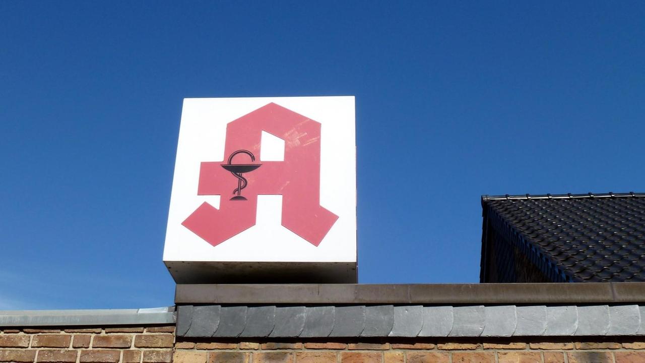 Das rote Apotheken-Logo auf dem Dach von einem Haus