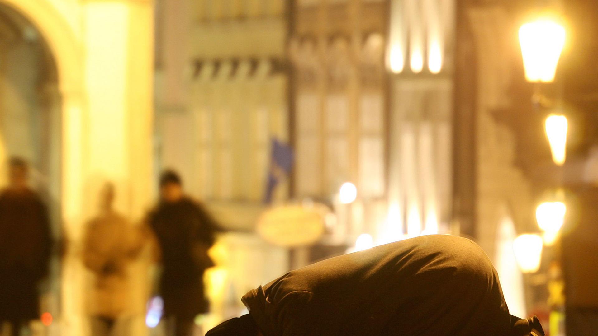 Ein Bettler kniet auf der Karlsbrücke in Prag am Boden.
