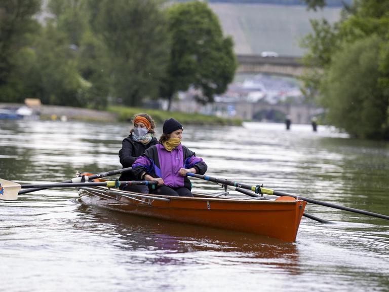Zwei Ruderinnen mit Mundbedeckung in einem Ruderboot in Würzburg.