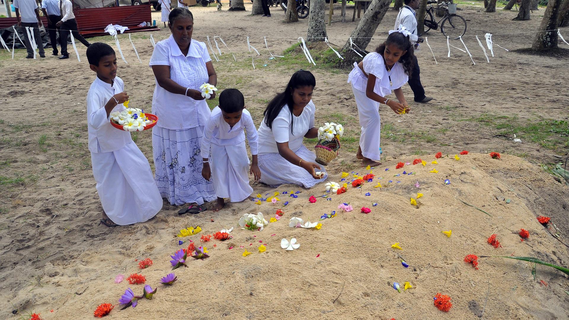 Trauernde legen Blumen an Gräbern von Tsunami-Opfern ab, die der Flutwelle vom Dezember 2004 zum Opfer fielen.