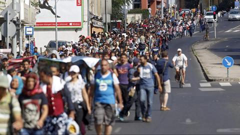 Flüchtlinge laufen eine Straße in Budapest entlang.