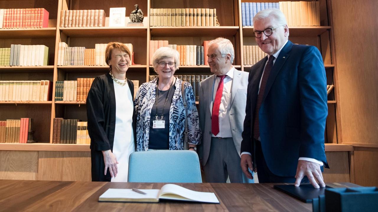 Bundespräsident Frank-Walter Steinmeier, Elke Büdenbender, Fridolin Mann und Christine Mann stehen im ehemaligen Arbeitszimmer von Thomas Mann, das in warmem Licht gehalten ist.Im Hintergrund befinden sich zahlreiche Bücher im Regal.