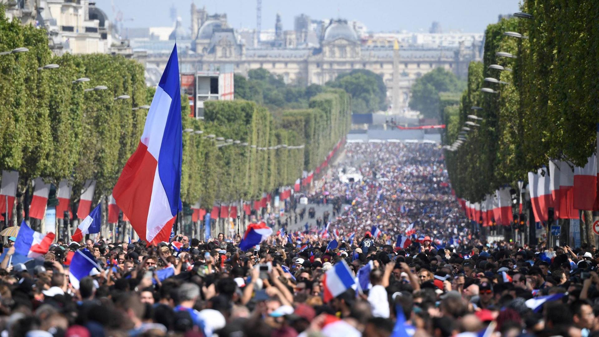 Zehntausende Menschen feiern auf dem Boulevard Champs-Elysees den Fußball-Weltmeister, die französische Nationalmannschaft.