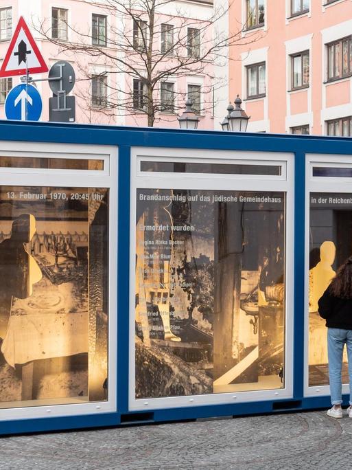 Durch eine Schaufensterscheibe kann man an der einen Seite in das Innere des Gedenk-Containers sehen – die Fotos aus den Wohnungen der Toten – einen Tag nach dem Anschlag.