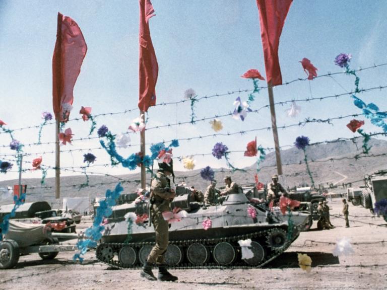 Sowjetische Armeefahrzeuge und Panzer am 15. Mai 1988 hinter einem mit künstlichen Blumen und roten Fahnen dekorierten Stacheldrahtzaun: An diesem Tag begann der sowjetischeTruppenabzug.