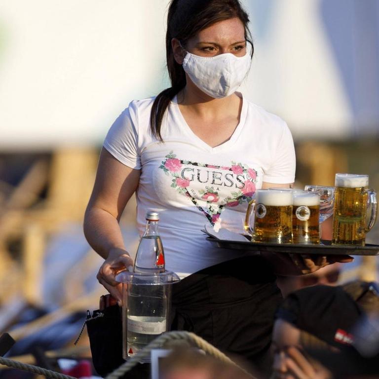 Eine Bedienung bringt Getränke beim Konzert von Mia Julia im Kulturgarten in der Bonner Rheinaue. Das Bonn Live Kulturgarten Open Air Festival 2020 ist Europas erstes Open Air Festival unter Corona-Auflagen wegen der Covid-19 Pandemie. Bedienungen tragen hier zum Schutz der Gäste Mundschutz. Bonn, 08.08.2020 *** A waitress brings drinks at Mia Julias concert in the Kulturgarten in the Rheinaue in Bonn The Bonn Live Kulturgarten Open Air Festival 2020 is Europes first open air festival under corona conditions due to the Covid 19 pandemic Waitresses wear face masks to protect the guests Bonn, 08 08 2020 Foto:xC.xHardtx/xFuturexImage