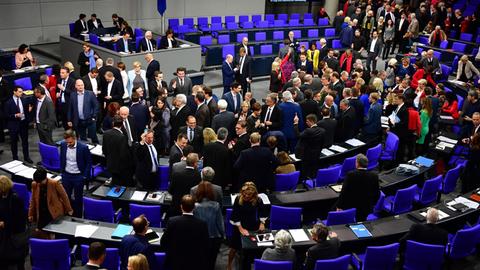 Abgeordnete stehen im Plenarsaal des Bundestages zwischen den Stühlen und unterhalten sich.