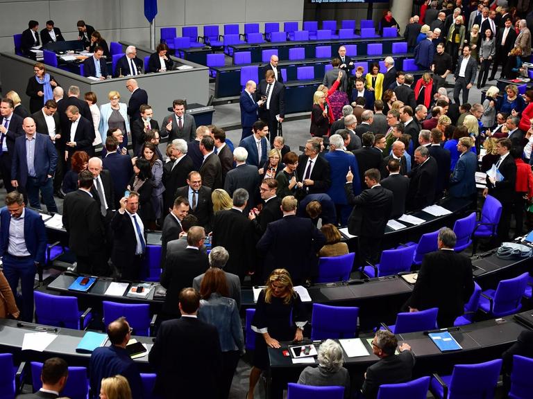 Abgeordnete stehen im Plenarsaal des Bundestages zwischen den Stühlen und unterhalten sich.