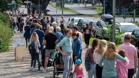 Zahlreiche Menschen stehen in einer langen Schlange vor den Wahllokalen im Tiergarten Gymnasium in der Altonaer Straße in Berlin.