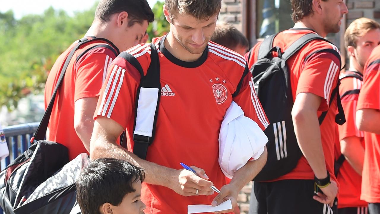 Fußballer Thomas Müller gibt einen kleinen Jungen im Brasilien-Trikot ein Autogramm am Rande der Weltmeisterschaft 2014.