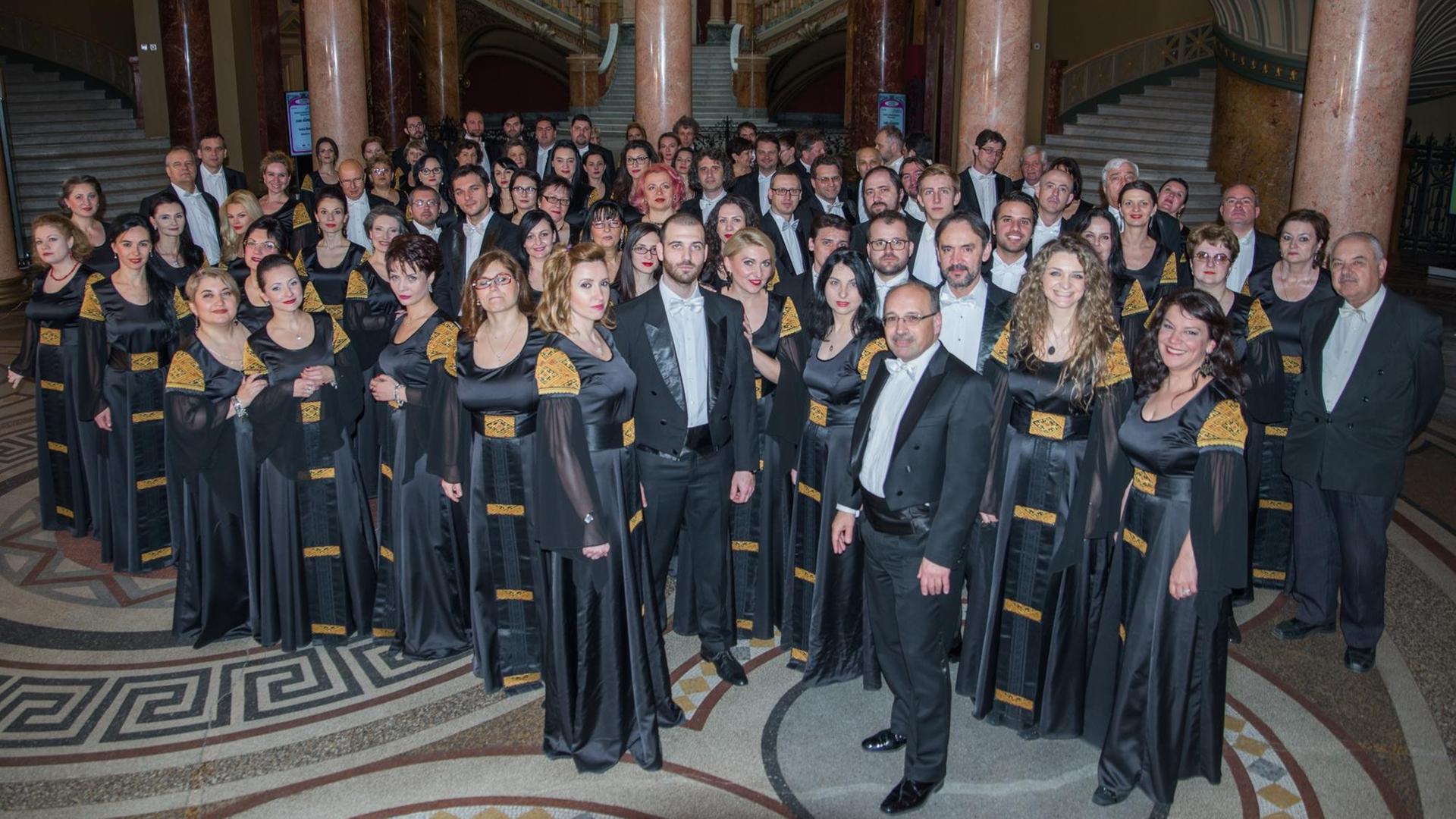 Der Philharmonische Chor „George Enescu“ steht in Auftrittsgarderobe versammelt um den Dirigenten