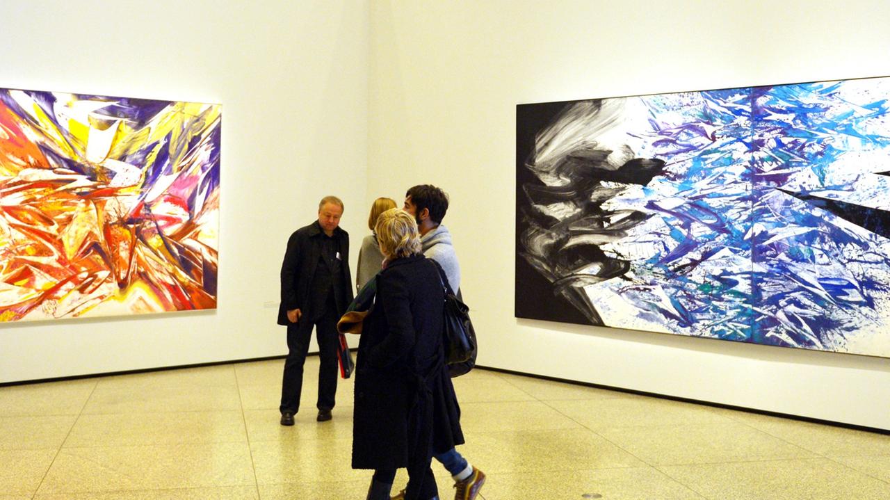 Besucher in der Werkschau von K.O. Götz in der Neuen Nationalgalerie vor abstrakten Malereien des Künstlers.