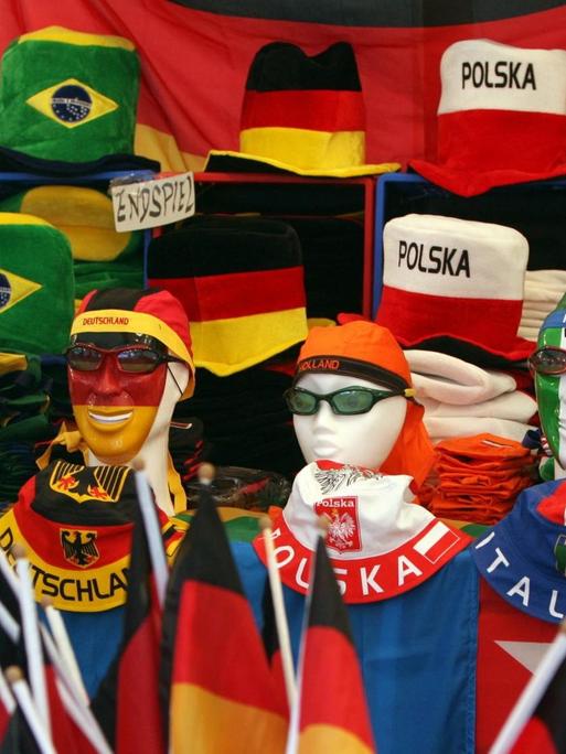 Fahnen, Kappen und Hüte in den Farben verschiedener Nationen dekorativ aufgestapelt