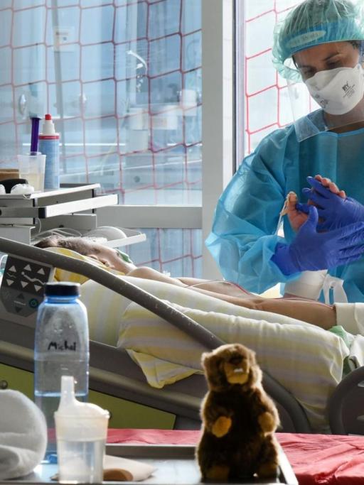 Auf der Covid-Station, einem Bereich der Operativen Intensivstation des Universitätsklinikums Leipzig, steht eine Physiotherapeutin am Bett einer Patientin.
