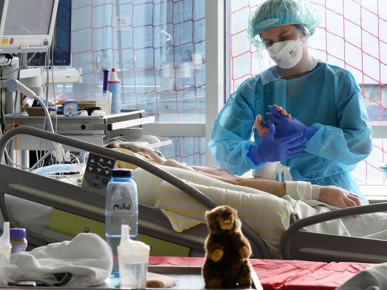 Auf der Covid-Station, einem Bereich der Operativen Intensivstation des Universitätsklinikums Leipzig, steht eine Physiotherapeutin am Bett einer Patientin.