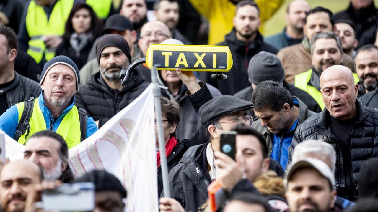 Eine Teilnehmerin hält bei einer Kundgebung von Taxifahrern am Bundesverkehrsministerium ein Taxi-Dachschild in die Höhe. 