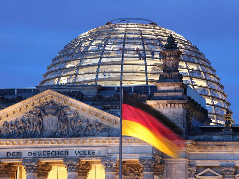 Vor der Reichstagskuppel und dem Reichstag weht eine schwarz-rot-goldene Deutschland-Fahne