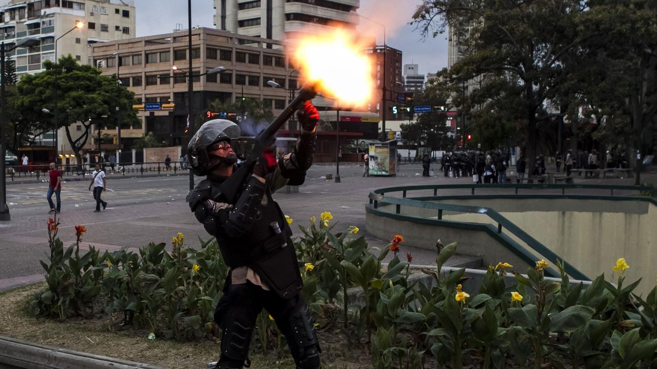 Ein Mitglied der venezolanischen Nationalpolizei schießt einen Tränengaskanister mit einem Gewehr ab, um regierungskritische Demonstranten zu vertreiben.