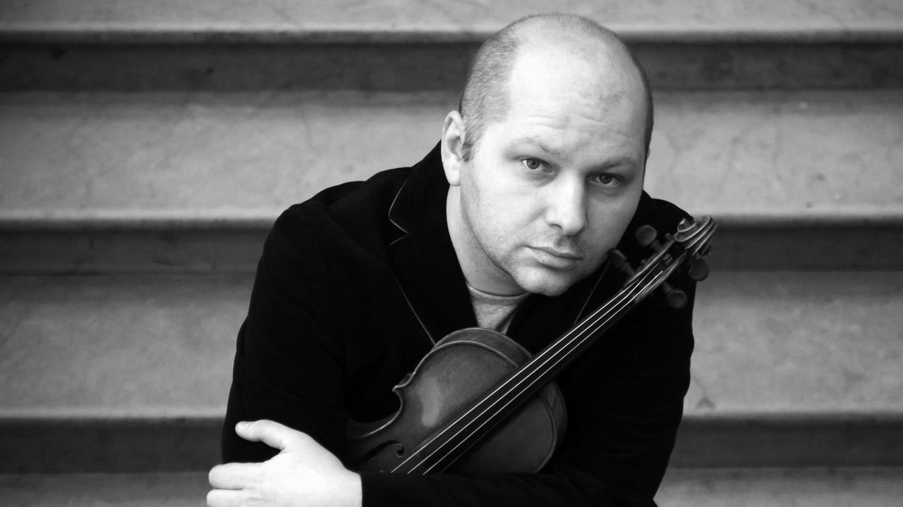 Porträt des Geigers, der auf einer Treppe sitzt und seine Geige umarmt.