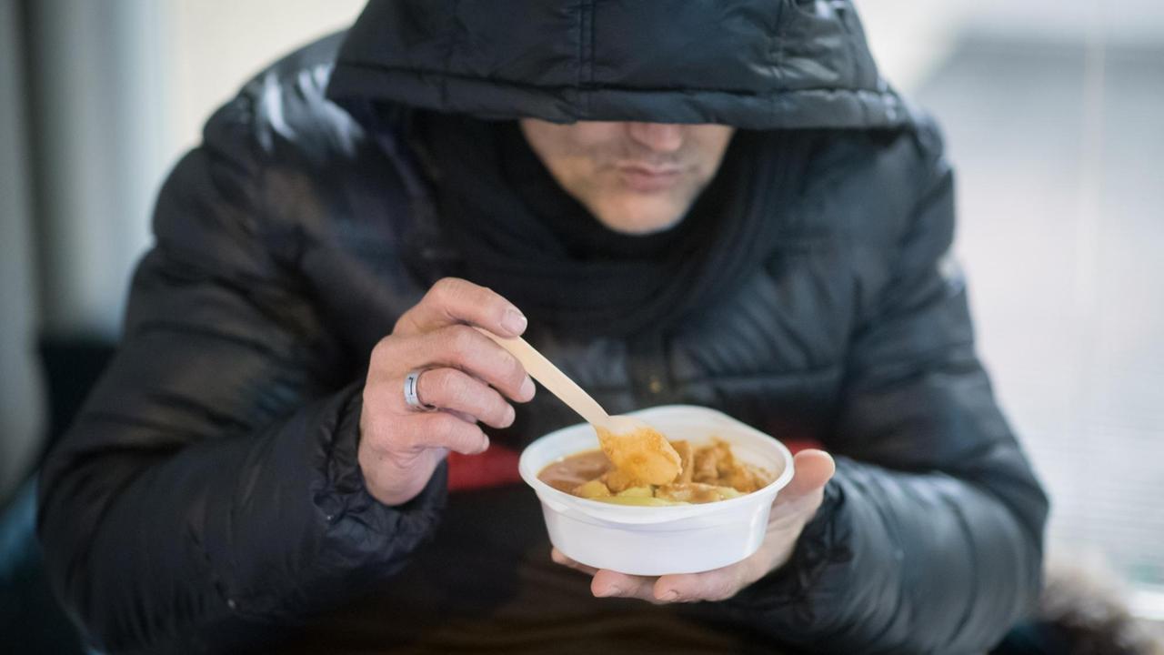 Ein Obdachloser isst in der Nacht am 06.01.2017 bei minus zehn Grad Celsius in der Nähe vom Stachus in München (Bayern) eine warme Mahlzeit, die er von den Helfern des Kältebusses erhalten hat. 