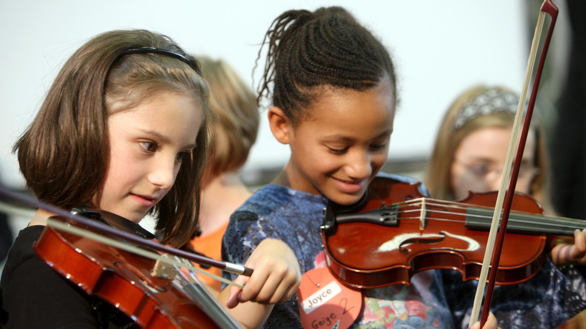 Zwei Mädchen spielen Geige.