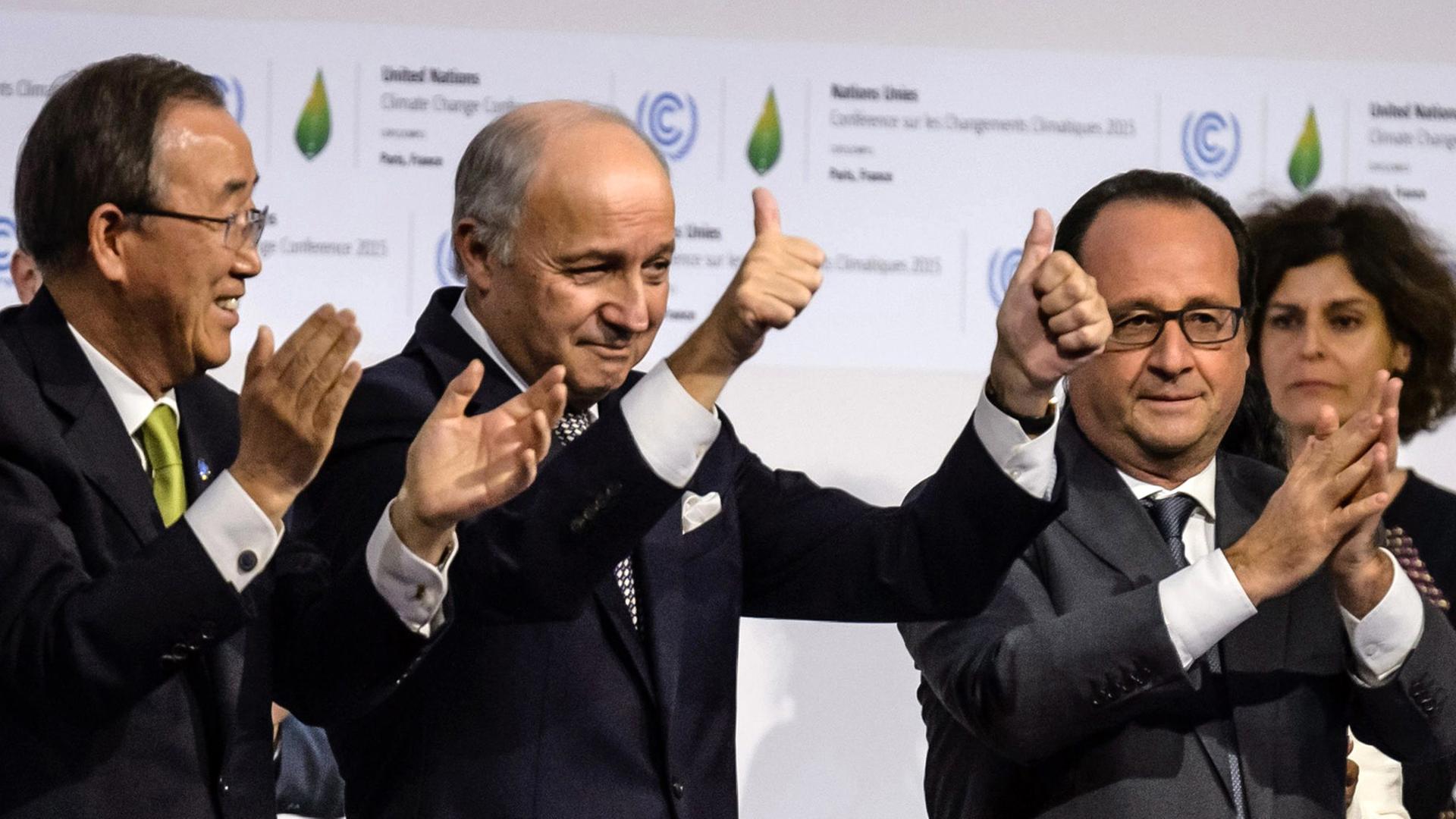 Der französische Präsident Francois Hollande (r.-l.), der französische Außenminister Laurent Fabius und der Generalsekretär der Vereinten Nationen Ban Ki-moon applaudieren nach der Unterzeichnung des Weltklima-Vertrags in Paris, am 12. Dezember 2015