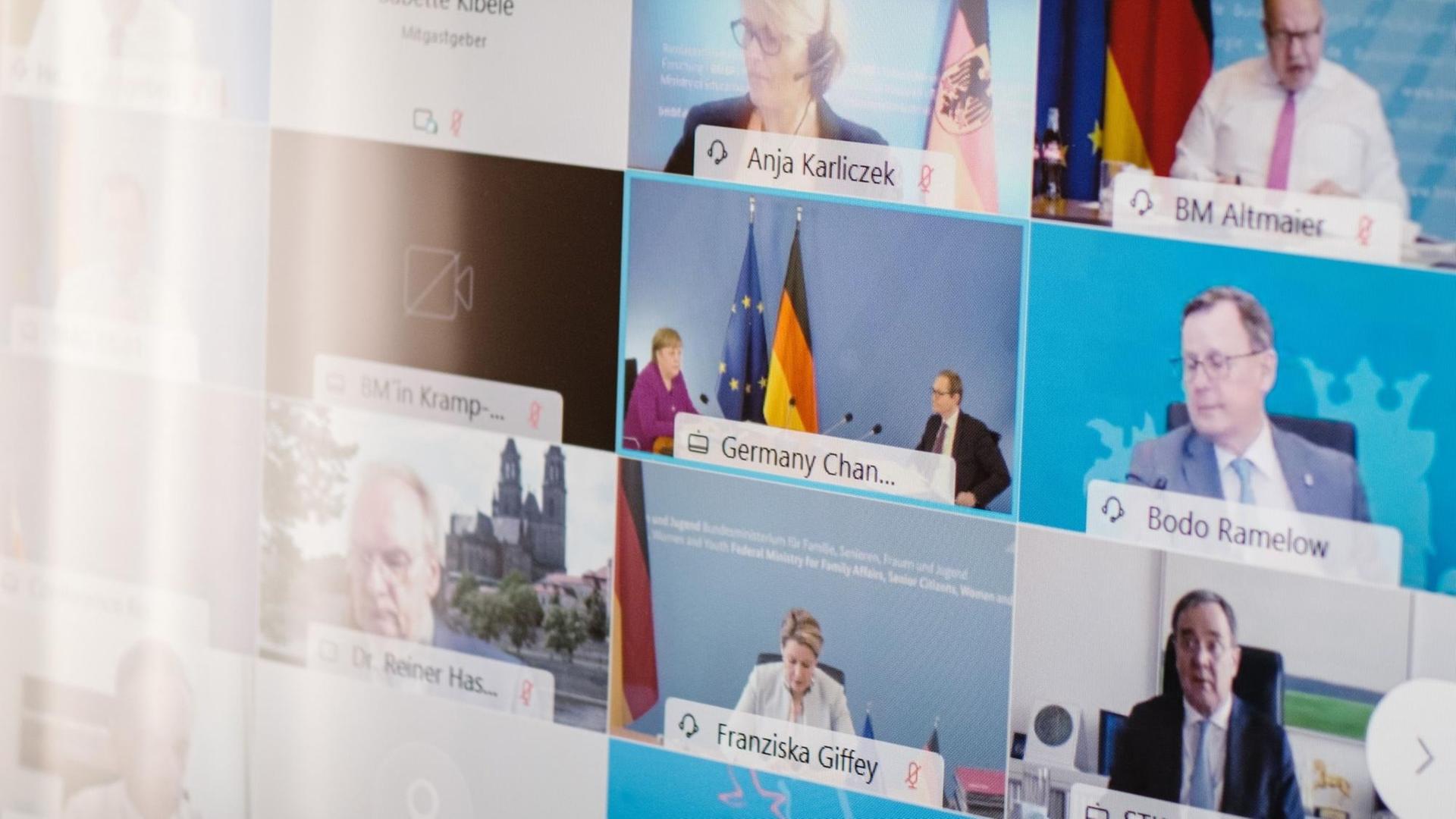 Auf einer Leinwand sind die Gesichter von führenden deutschen Politikerinnen und Politikern zu sehen. 