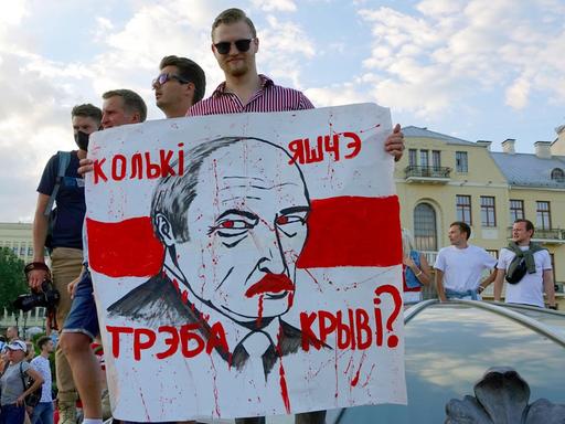 "Wie viel Blut braucht es noch?" steht auf dem Plakat mit dem Gesicht von Machthaber Lukaschenko, das ein junger Mann auf dem Unabhängigkeitsplatz in Minsk in der Hand hält. 16.08.2020 "Wie viel Blut braucht es noch?" steht auf dem Plakat mit dem Gesicht von Machthaber Lukaschenko, das ein junger Mann auf dem Unabhängigkeitsplatz in Minsk in der Hand hält. 16.08.2020