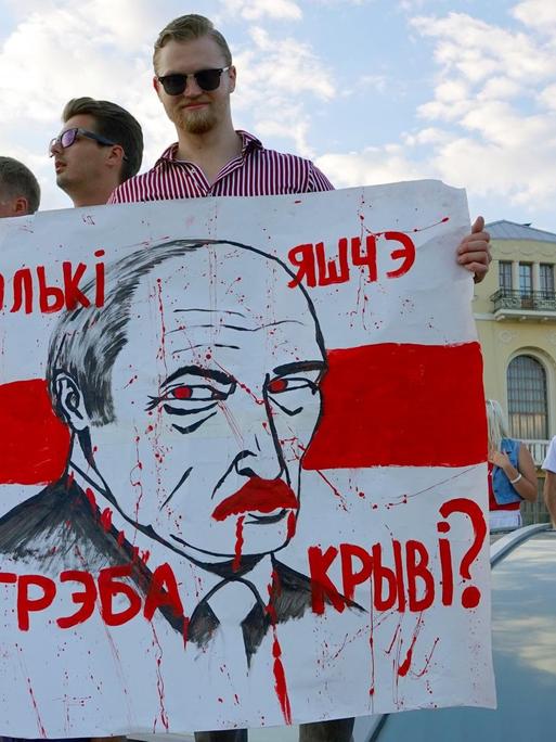 "Wie viel Blut braucht es noch?" steht auf dem Plakat mit dem Gesicht von Machthaber Lukaschenko, das ein junger Mann auf dem Unabhängigkeitsplatz in Minsk in der Hand hält. 16.08.2020