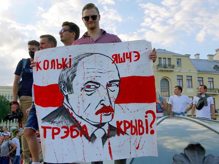 "Wie viel Blut braucht es noch?" steht auf dem Plakat mit dem Gesicht von Machthaber Lukaschenko, das ein junger Mann auf dem Unabhängigkeitsplatz in Minsk in der Hand hält. 16.08.2020