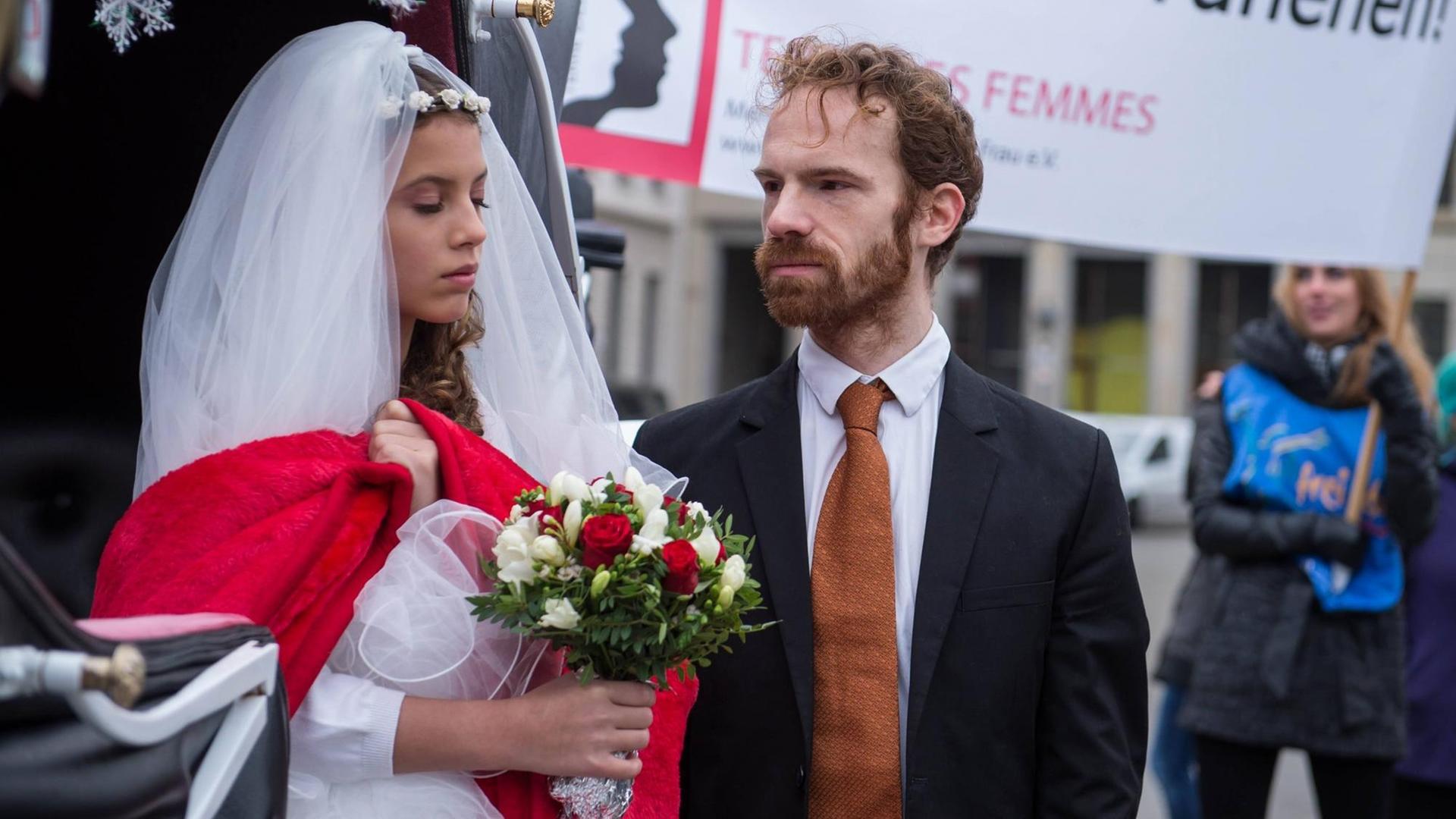 Zwei Darsteller von "Terre des Femmes" spielen ein junges Mädchen im Hochzeitskleid und einen älteren Mann im Anzug