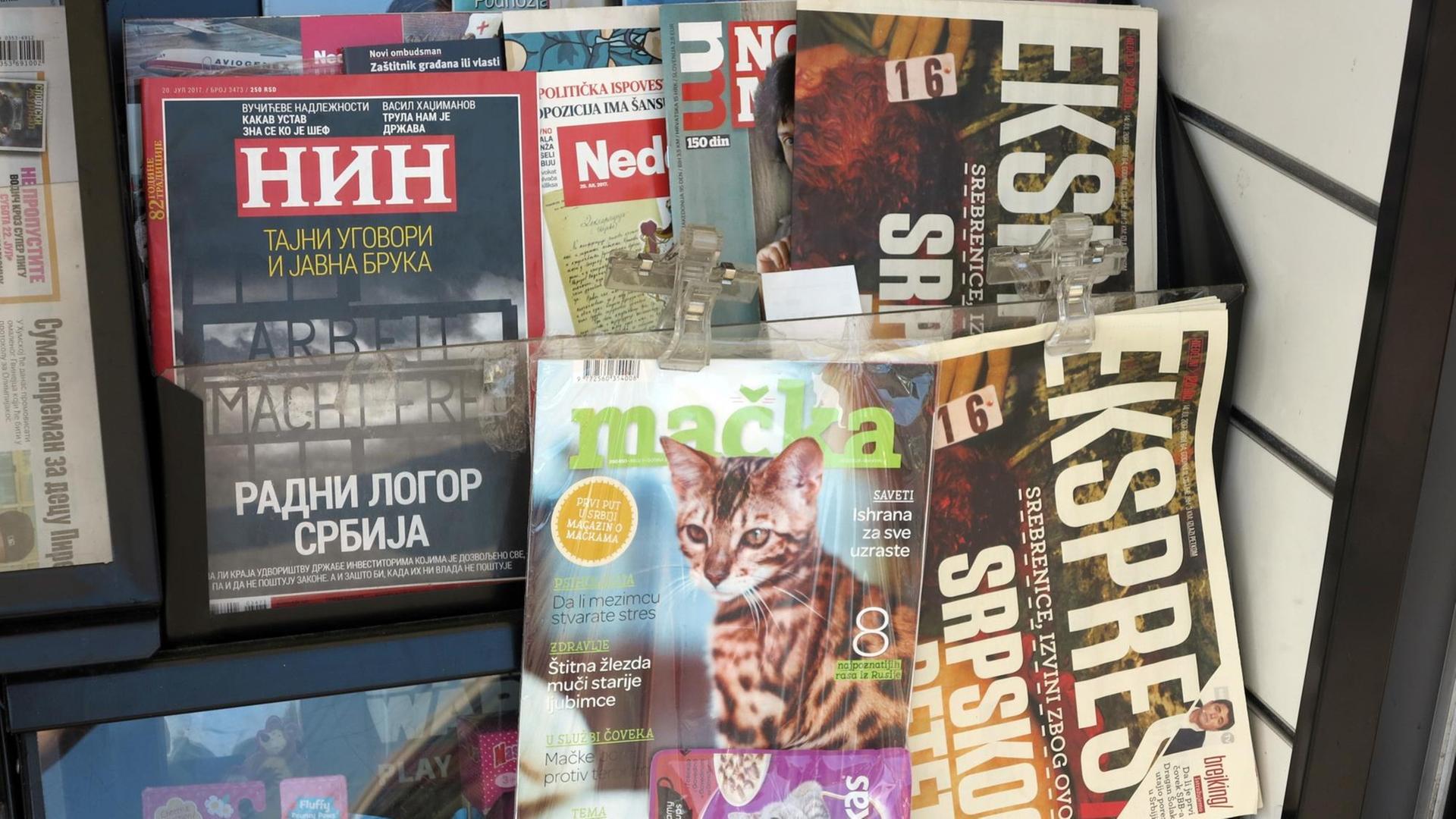 Zeitschriften an einem Kiosk, darunter das Nachrichtenmagazin NIN mit dem nationalsozialistischen KZ-Motto "Arbeit macht frei" auf dem Titelblatt