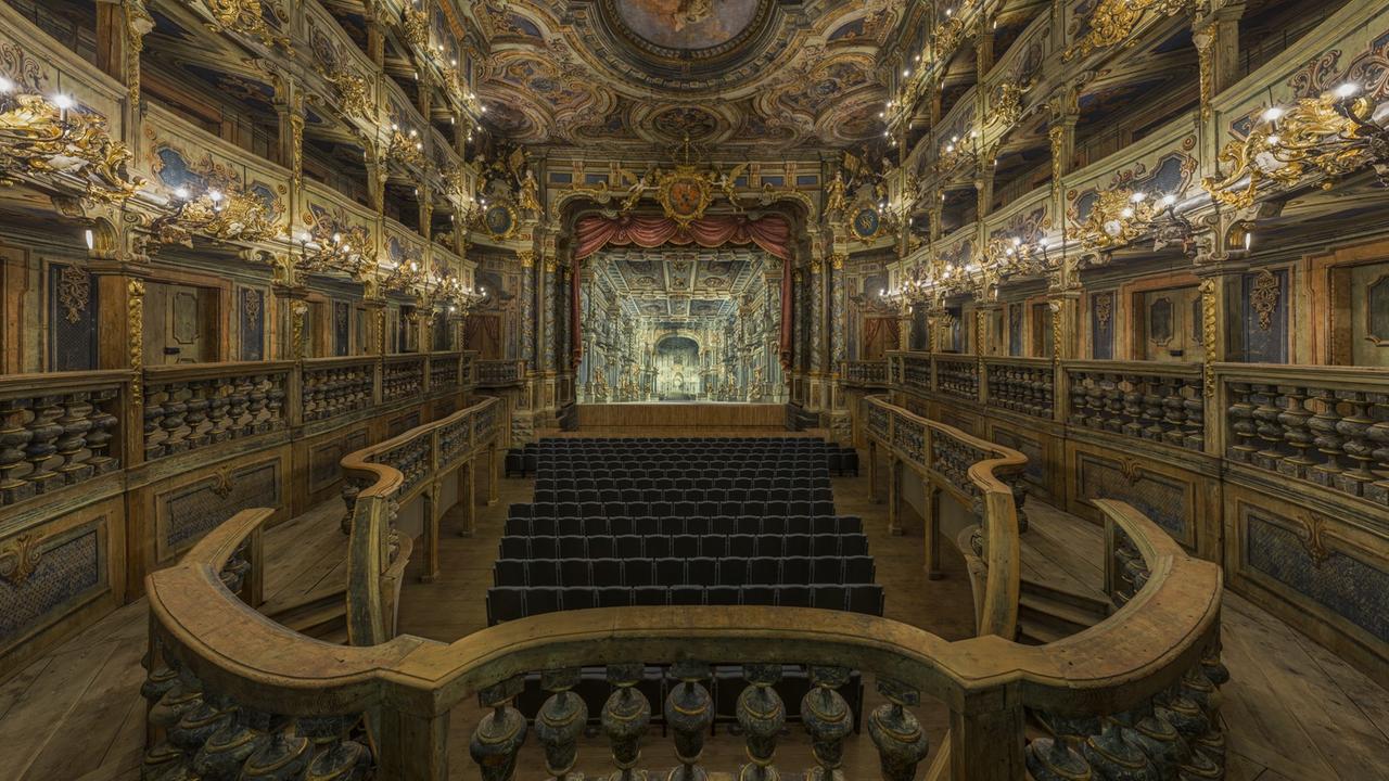 Blick in den barocken Zuschauerraum zur Bühne, die mit barockem Bühnenbild versehen ist.