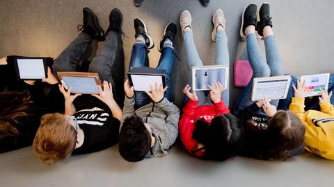 Schüler sitzen in einer Reihe und lernen mit Laptops.