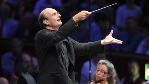 Der Dirigent Andrew Manze mit Taktstock im Vordergrund, im Hintergrund das Deutsche Symphonie-Orchester Berlin.