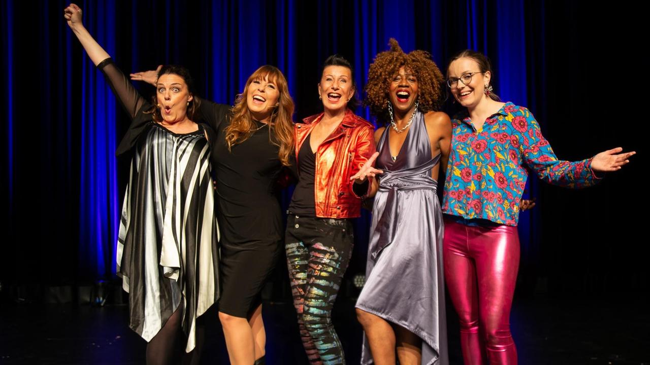 Fünf Kabarettistinnen stehen auf einer Bühne nebeneinander: Rebecca Carrington, Katie Freundenschuss, Patrizia Moresco, Tamika Campbell, Helene Bockhorst