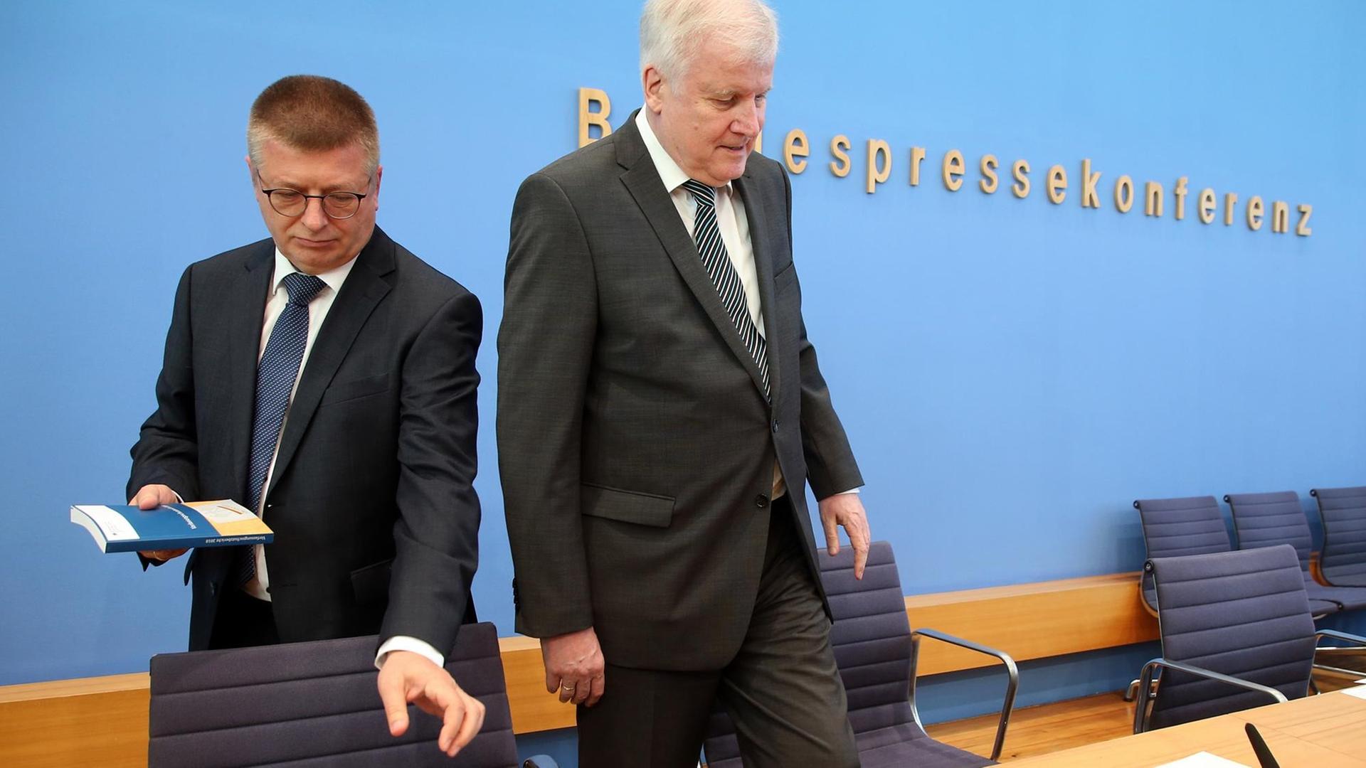 Horst Seehofer (CSU), Bundesinnenminister, und Thomas Haldenwang (l), Präsident des Bundesamtes für Verfassungsschutz, stellen vor der Bundespressekonferenz den Verfassungsschutzbericht 2018 vor und nehmen ihre Plätze ein.